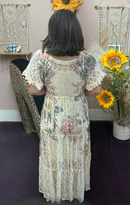 Person wearing a floral dress holding sunflowers in a room with decorative wall hangings.